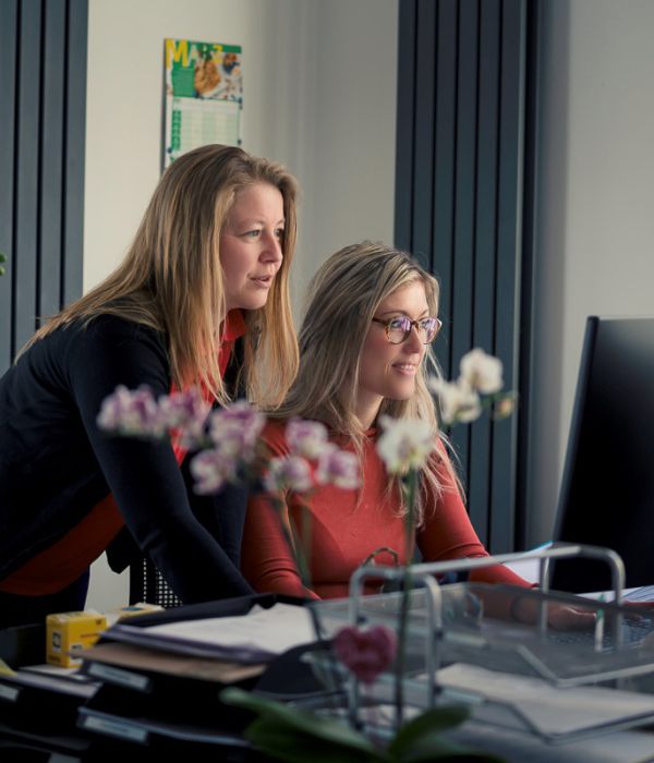 Zwei Mitarbeiterinnen der Steuerkanzlei arbeiten gemeinsam am Bildschirm im modernen Büro